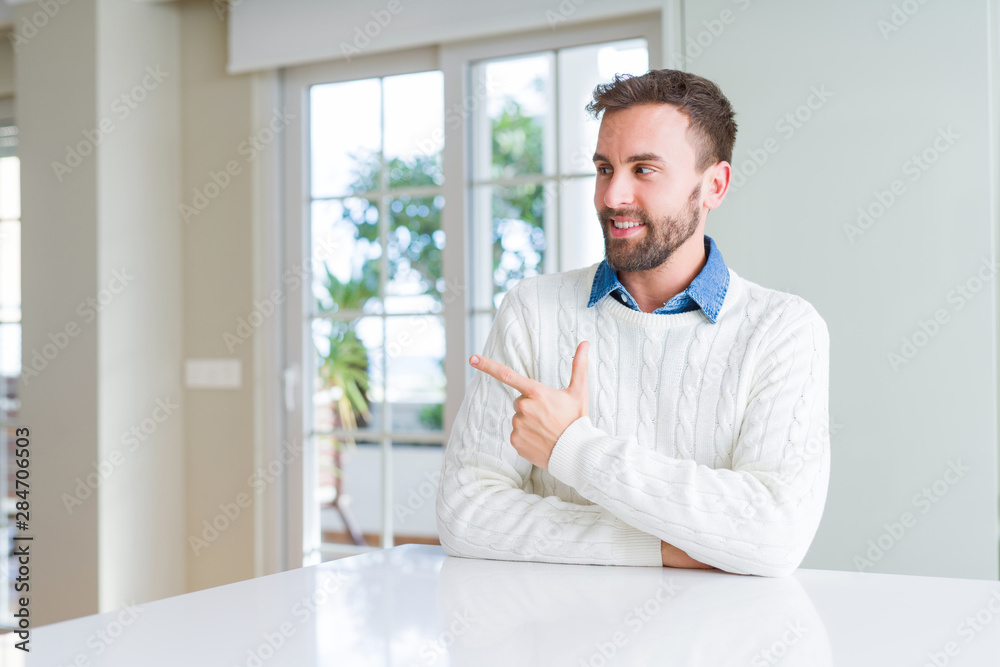 Handsome man wearing casual sweater cheerful with a smile of face pointing with hand and finger up to the side with happy and natural expression on face Handsome man wearing casual sweater cheerful with a smile of face pointing with hand and finger up to the side with happy and natural expression on face