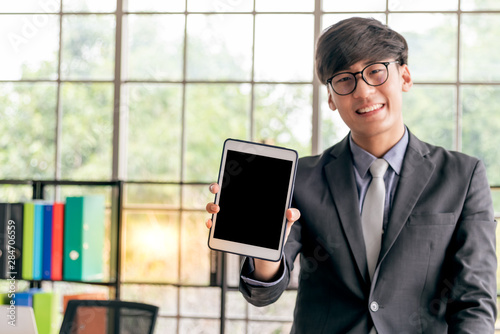 Asian businessmen Show tablet Held ind the hand, which is a tool That makes him work easier In communication and Store business data, at workplace, to technoly and business concept. photo