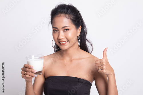 Healthy Asian woman drinking a glass of milk thumbs up.