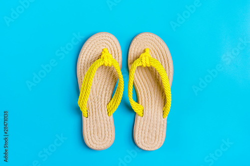 Eco yellow bamboo flip flops on blue background Flat lay, top view. Zero waste, plastic free, holiday, summer, vacation concept. 