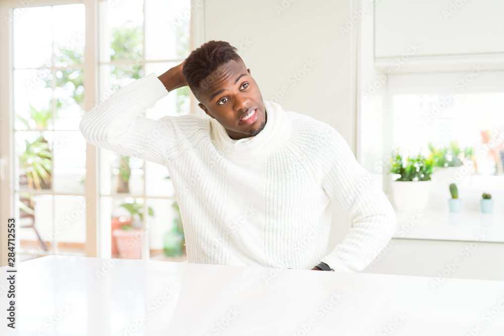 Handsome african american man on white table confuse and wonder about question. Uncertain with doubt, thinking with hand on head. Pensive concept.