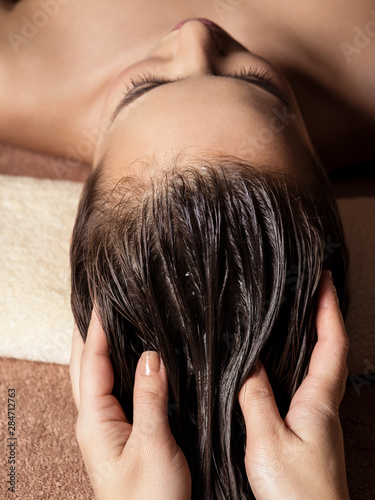 Cosmetologist massaging hair on the head of the woman. Spa treatments.