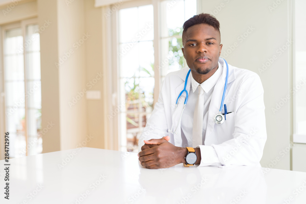 African american doctor man at the clinic Relaxed with serious expression on face. Simple and natural looking at the camera.