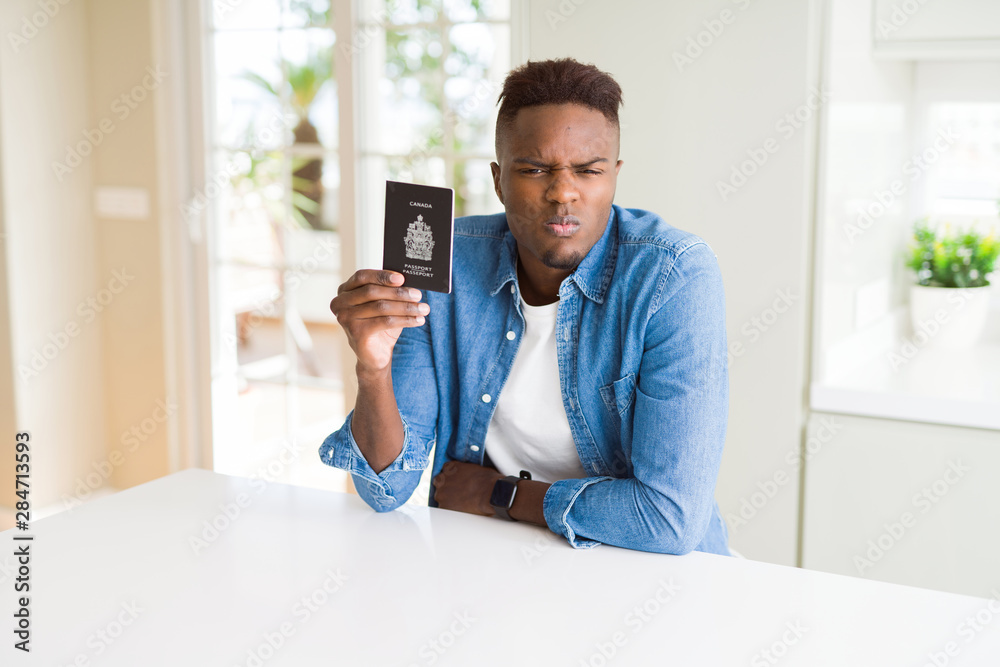 African american man holding passport of Canada with a confident expression on smart face thinking serious