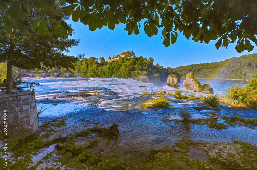 Naklejka premium Early in the morning at sunrise, a few hours before onslaught of tourists, at the Rhine Falls, near the city of Schaffhausen,, more precisely in Neuhausen, Switzerland. Summer 2019, month of August.