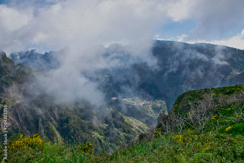View from the hiking trail at the Boca da Corrida belvedere on the Encumeada pass on Madeira Island, Portugal in summer, View to the village of Curral das Freiras View from the hiking trail at the Boca da Corrida belvedere on the Encumeada pass on Madeira Island, Portugal in summer, View to the village of Curral das Freiras