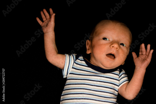A 3 Week Old Baby Poses on a Black Background. Perfect for Memes with Copy Space.