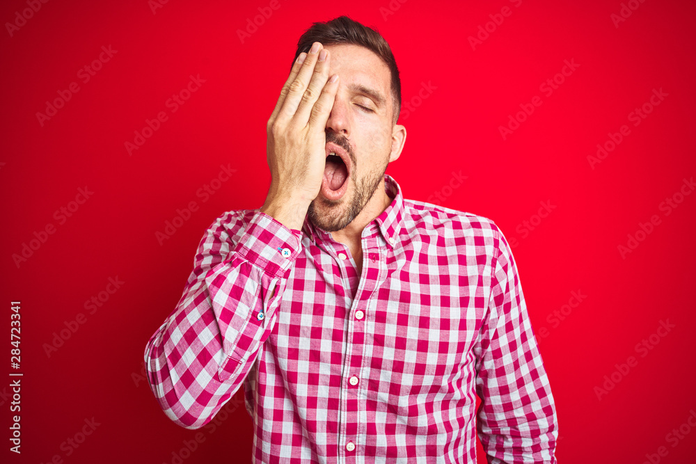 Young handsome man over red isolated background Yawning tired covering half face, eye and mouth with hand. Face hurts in pain. Young handsome man over red isolated background Yawning tired covering half face, eye and mouth with hand. Face hurts in pain.