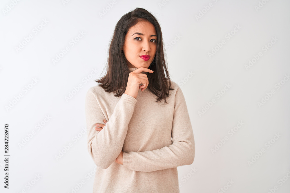 Beautiful chinese woman wearing turtleneck sweater standing over isolated white background looking confident at the camera smiling with crossed arms and hand raised on chin. Thinking positive. Beautiful chinese woman wearing turtleneck sweater standing over isolated white background looking confident at the camera smiling with crossed arms and hand raised on chin. Thinking positive.