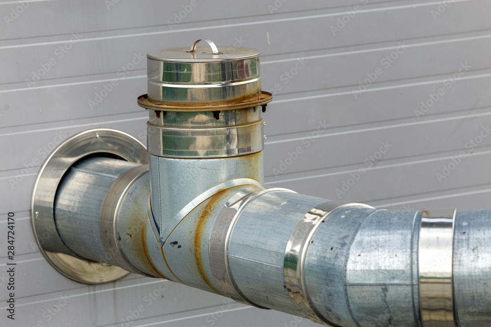 Metallic exhaust smoke pipes installed on house exterior wall. Metallic exhaust smoke pipes installed on house exterior wall.
