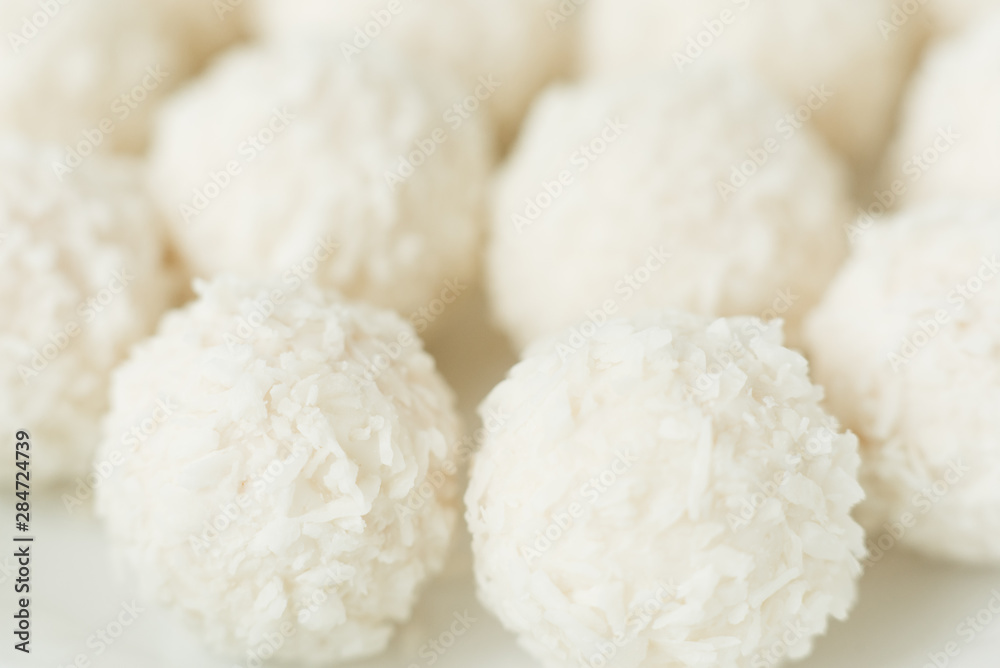 Chocolate covered coconut candies on white plate isolated on white background. Truffle candy set. Selective focus