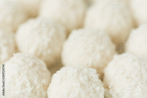 Chocolate covered coconut candies on white plate isolated on white background. Truffle candy set. Selective focus