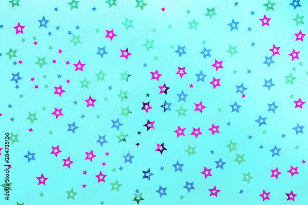 Multicolored stars sprinkles on pastel blue backdrop. Festive holiday background. for your projects. Celebration concept. Christmas pattern. Top view, flat lay