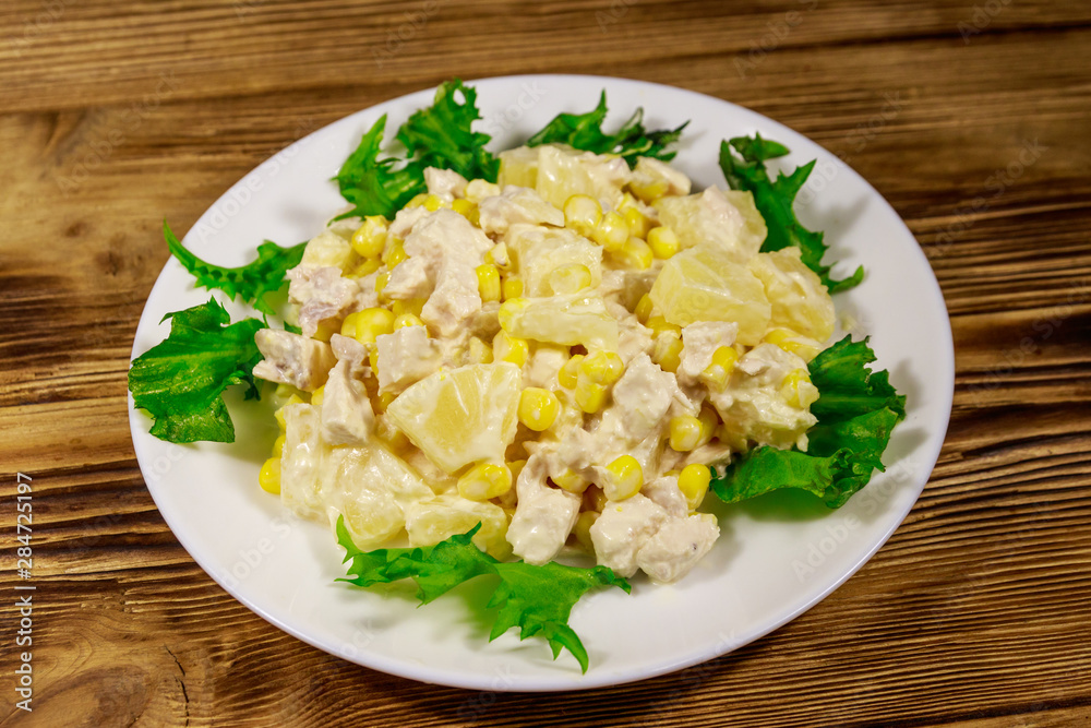 Festive salad with chicken breast, sweet corn, canned pineapple and mayonnaise on wooden table Festive salad with chicken breast, sweet corn, canned pineapple and mayonnaise on wooden table
