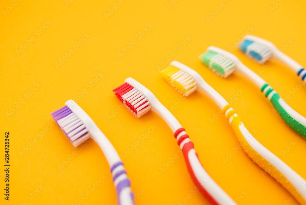 set of plastic toothbrushes on yellow background set of plastic toothbrushes on yellow background