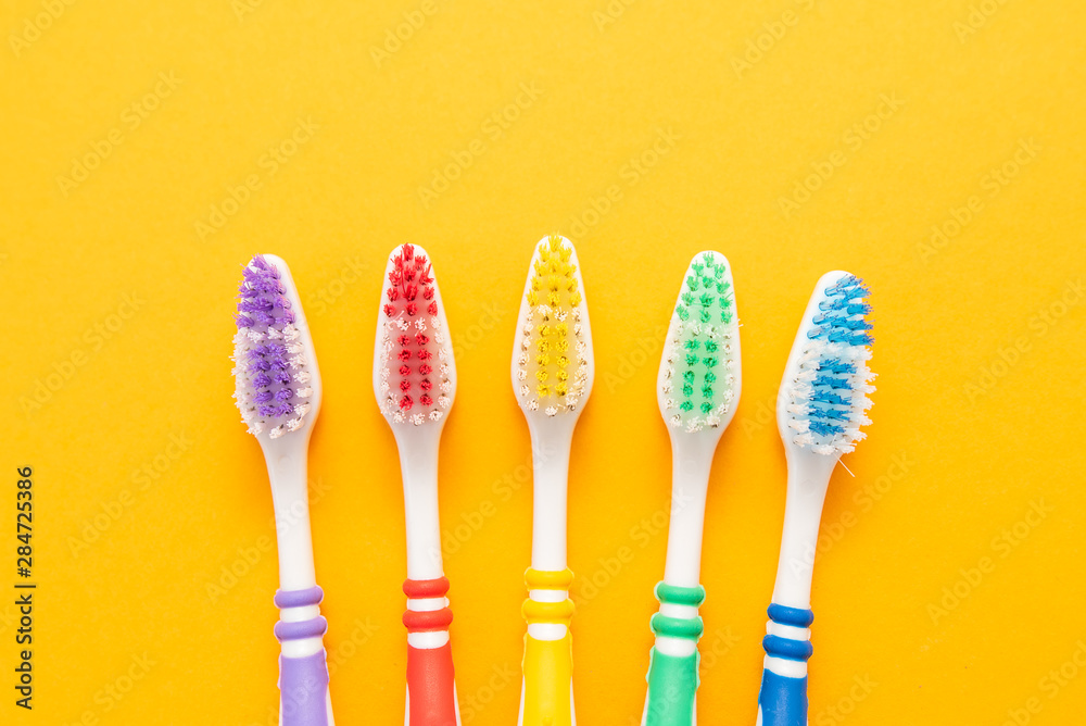 set of plastic toothbrushes on yellow background set of plastic toothbrushes on yellow background