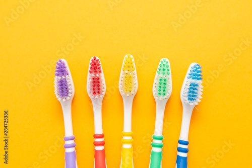 set of plastic toothbrushes on yellow background