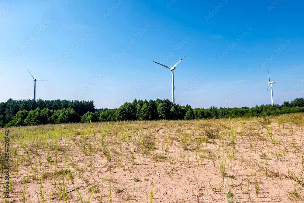 rotating blades of a windmill propeller on blue sky background. Wind power generation. Pure green energy.