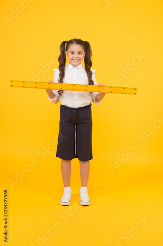Tell me about distance. Kid school uniform hold ruler. Pupil cute girl with big ruler. Geometry school subject. Education and school concept. Sizing and measuring. School student study geometry