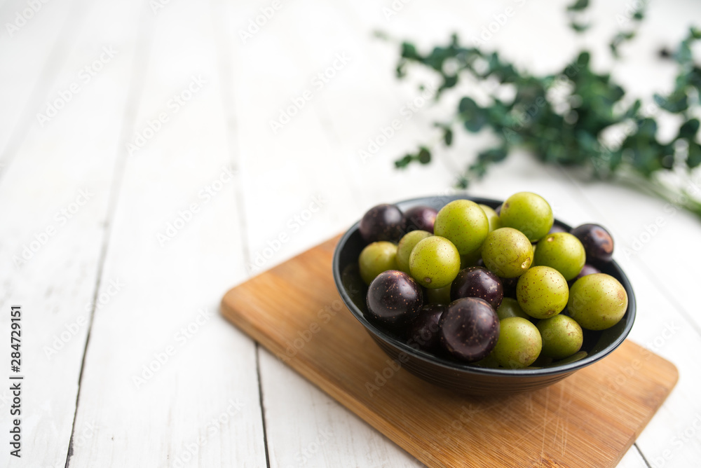Muscadine grapes are also known as swamp grapes, Florida grapes in a bowl on wood background Muscadine grapes are also known as swamp grapes, Florida grapes in a bowl on wood background