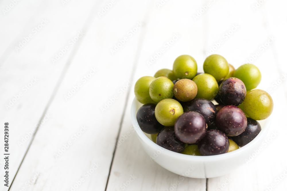Muscadine grapes are also known as swamp grapes, Florida grapes in a bowl on wood background Muscadine grapes are also known as swamp grapes, Florida grapes in a bowl on wood background