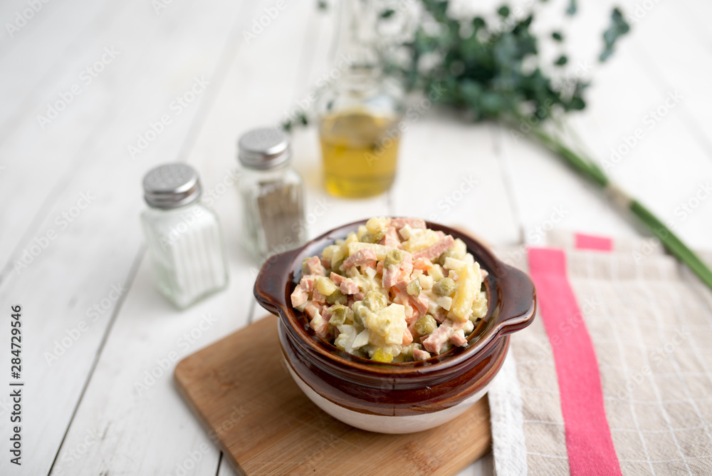 Bowl of traditional Russian salad called Olivie, Russian New Year or Christmas salad on wooden background. Salad from cooked vegetables. Potato salad. Bowl of traditional Russian salad called Olivie, Russian New Year or Christmas salad on wooden background. Salad from cooked vegetables. Potato salad.