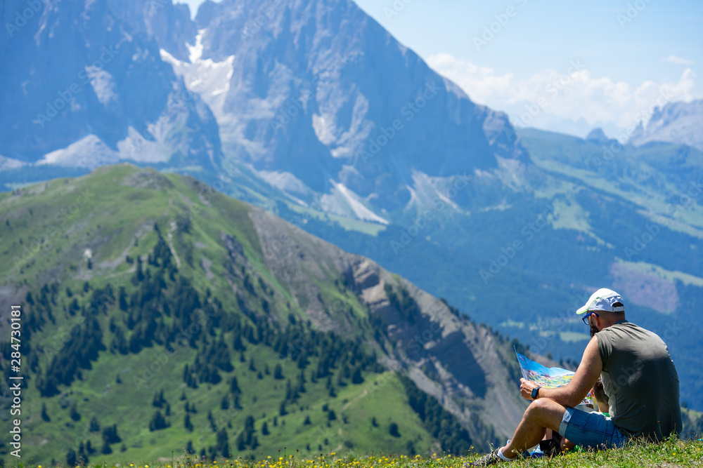 Naklejka premium un homme assis dans l'herbe au dessus d'une montagne regarde une carte