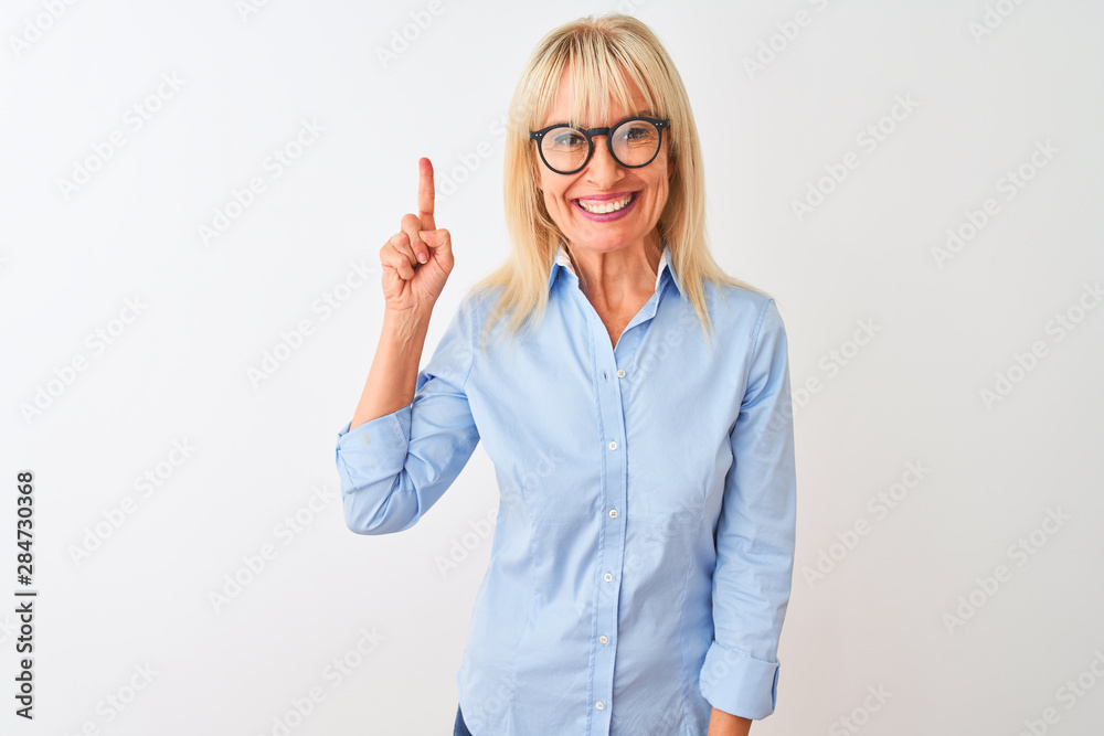 Middle age businesswoman wearing elegant shirt and glasses over isolated white background showing and pointing up with finger number one while smiling confident and happy.