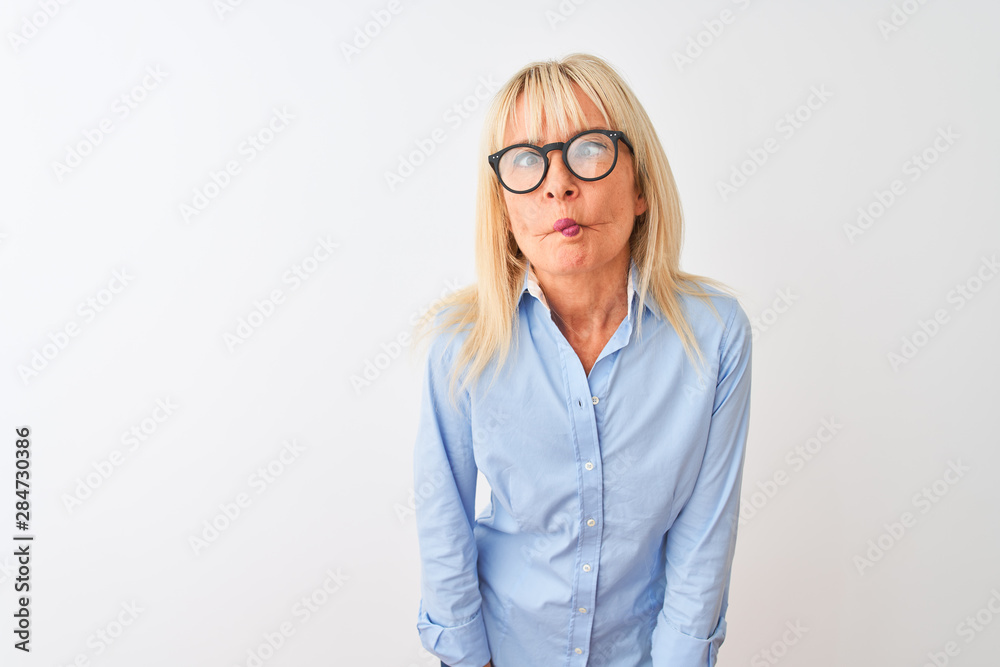 Middle age businesswoman wearing elegant shirt and glasses over isolated white background making fish face with lips, crazy and comical gesture. Funny expression.
