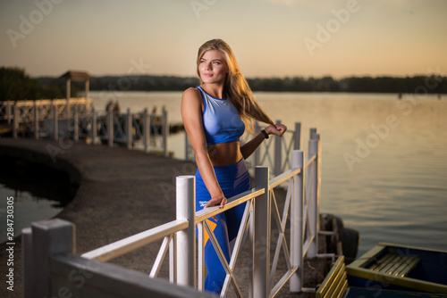 Beautiful sports girl posing on sunset background. Great body.