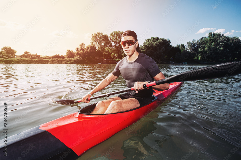 Sportsman kayaking on a lake while the sun setting