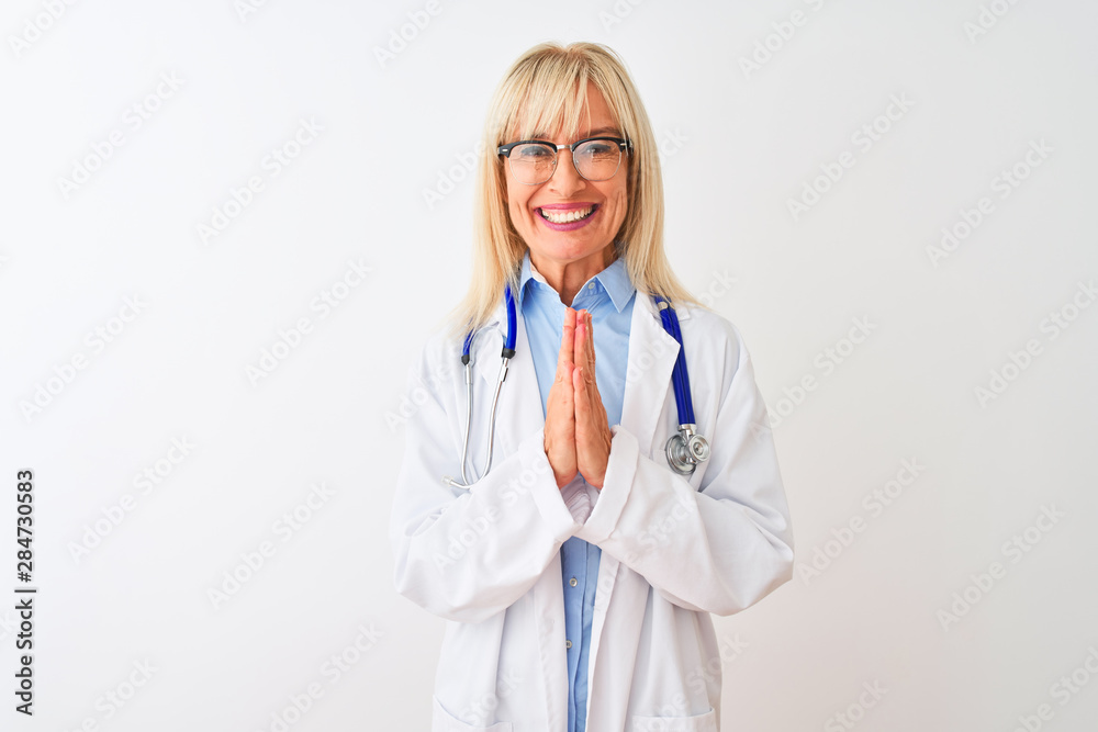 Middle age doctor woman wearing glasses and stethoscope over isolated white background praying with hands together asking for forgiveness smiling confident. Middle age doctor woman wearing glasses and stethoscope over isolated white background praying with hands together asking for forgiveness smiling confident.