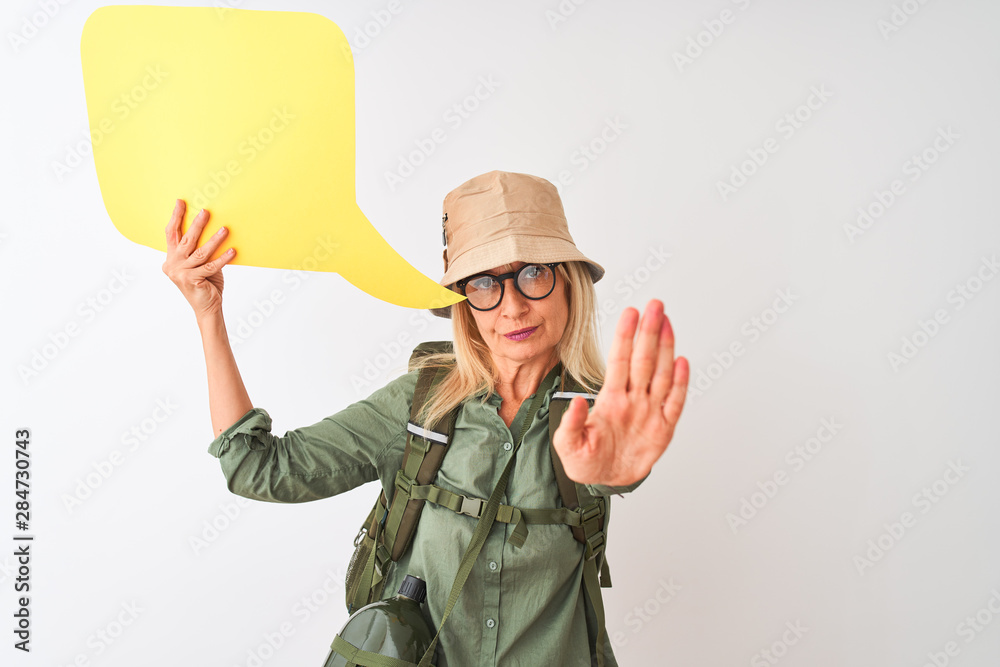 Senior hiker woman wearing canteen holding speech bubble over isolated white background with open hand doing stop sign with serious and confident expression, defense gesture Senior hiker woman wearing canteen holding speech bubble over isolated white background with open hand doing stop sign with serious and confident expression, defense gesture
