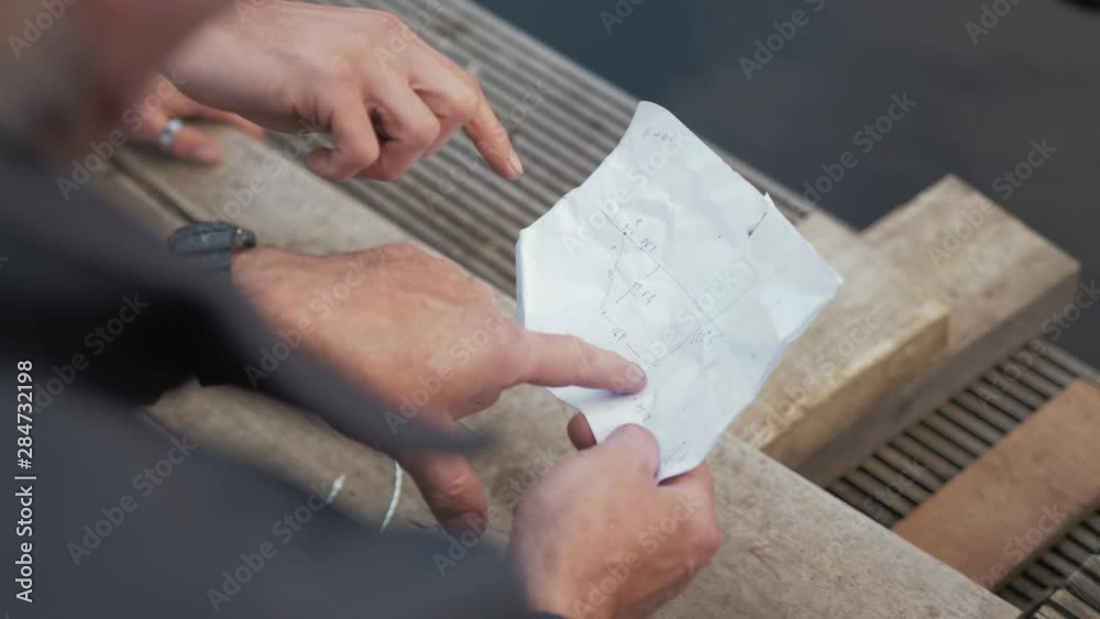 Two men discuss drawn plans pointing finger