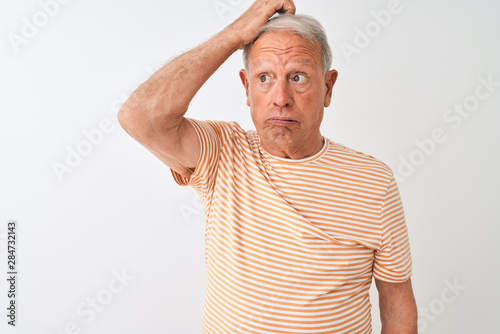 Senior grey-haired man wearing striped t-shirt standing over isolated white background confuse and wondering about question. Uncertain with doubt, thinking with hand on head. Pensive concept.