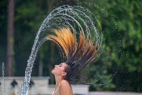 Woman flicking hair to make beautiful frozen water trail on swimming pool photo