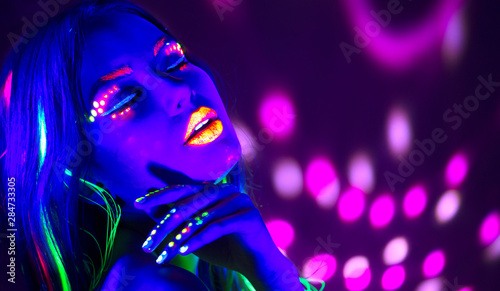 Fashion disco woman. Dancing model in neon light, portrait of beauty girl with fluorescent makeup. Art design