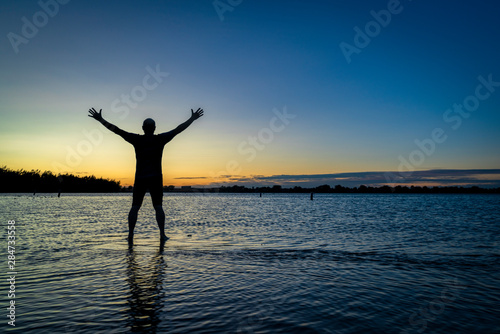 sunrise silhouette of a man on a lake