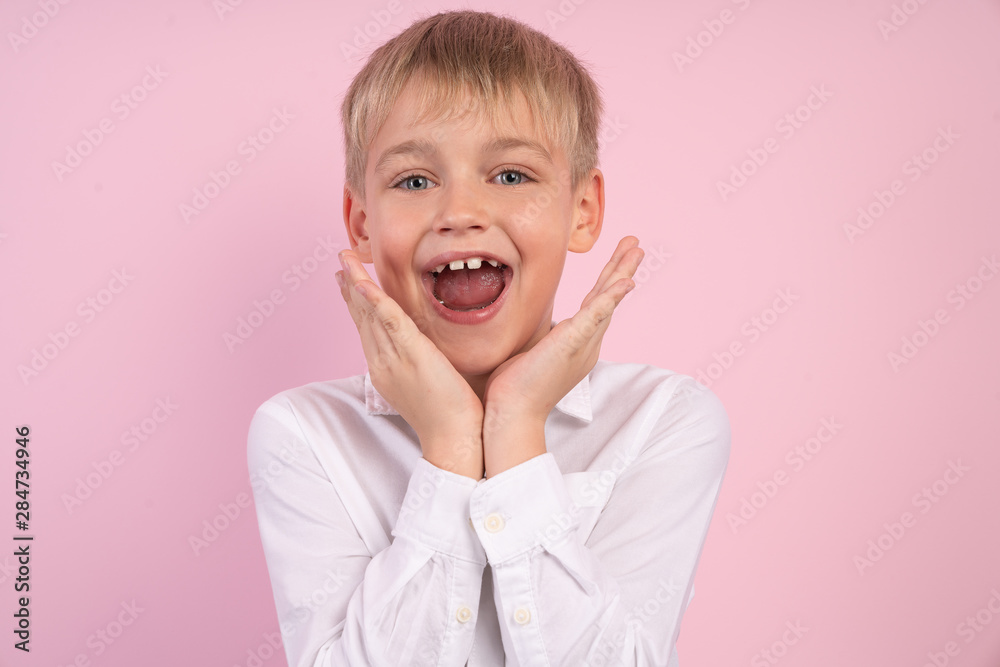 Closeup photo portrait of nice dreamy suprised amazed boy touching cheeks looking at camera isolated over pink background Closeup photo portrait of nice dreamy suprised amazed boy touching cheeks looking at camera isolated over pink background
