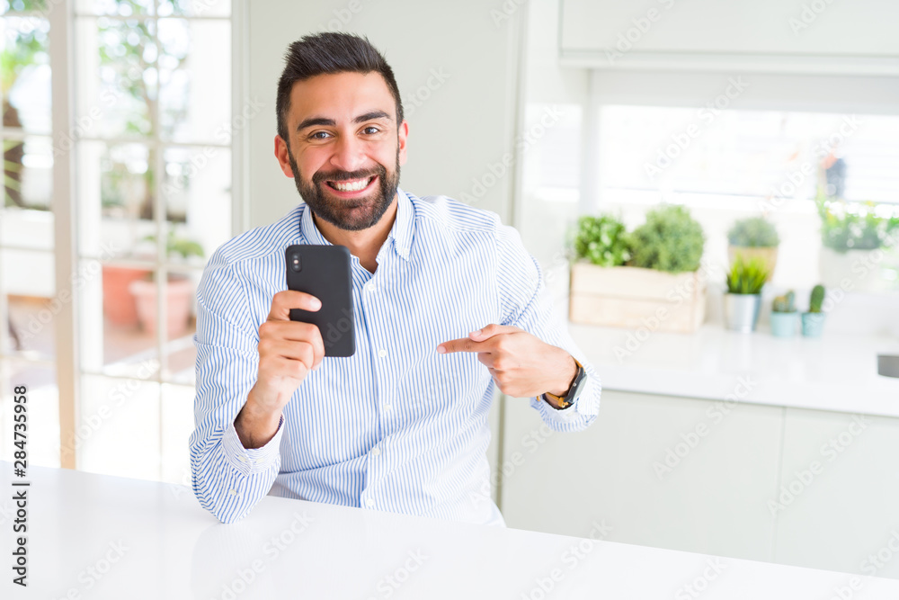 Handsome hispanic business man using smartphone with surprise face pointing finger to himself Handsome hispanic business man using smartphone with surprise face pointing finger to himself