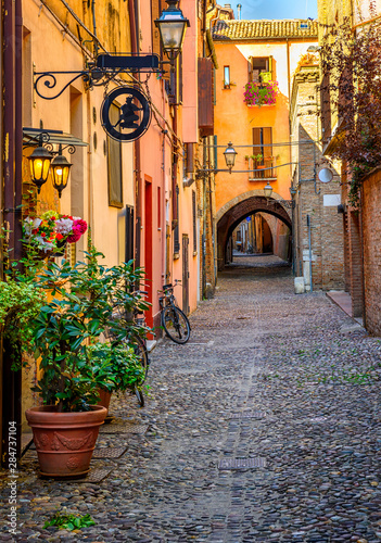 Fototapeta Naklejka Na Ścianę i Meble -  Cozy narrow street in Ferrara, Emilia-Romagna, Italy. Ferrara is capital of the Province of Ferrara
