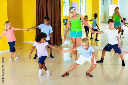 Group of children practicing vigorous jive movements in dance cl