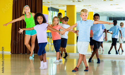 Fototapeta Naklejka Na Ścianę i Meble -  Group of children practicing vigorous jive movements in dance cl