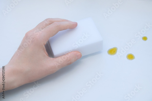 Melamine white sponge in a girls hand. Cleans dirt from a white table.