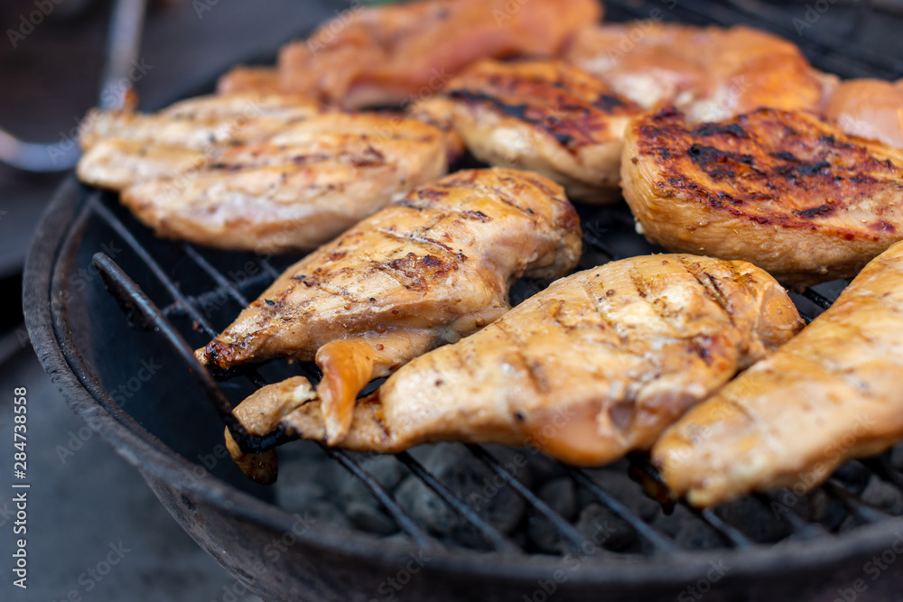 Whole large pieces of chicken meat are grilled. Street food concept.