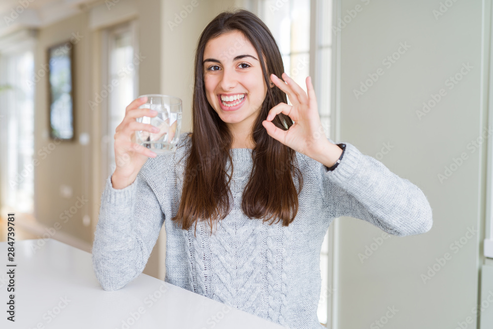 Beautiful young woman drinking a fresh glass of water doing ok sign with fingers, excellent symbol Beautiful young woman drinking a fresh glass of water doing ok sign with fingers, excellent symbol