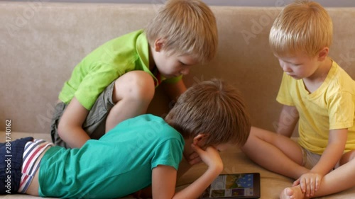 Happy calm children are playing with tablet. boys are happy together on vacation at their parents' house. Friendly joint preparation for school.