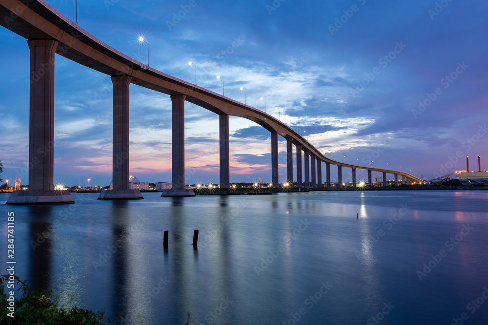 The Jordan Bridge over the Elizabeth River on the border of Norfolk and Chesapeake Virginia against a beautiful red, purple, pink, and blue sunset