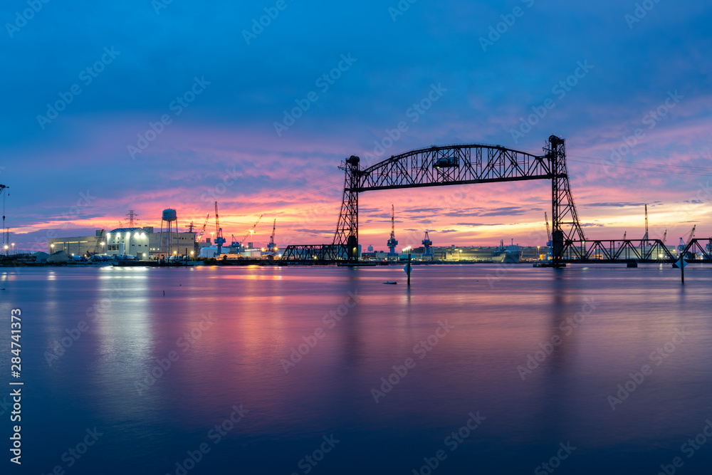 Vertical lift bridge for railroad over the Elizabeth River on the border of Norfolk and Chesapeake Virginia against a beautiful red, purple, pink, and blue sunset