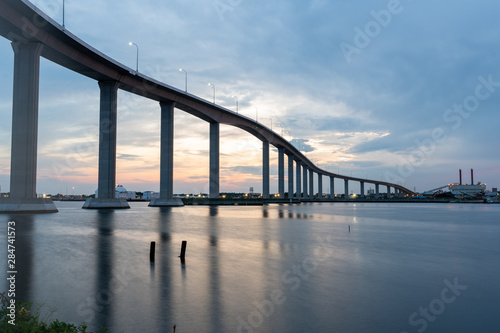 The Jordan Bridge over the Elizabeth River on the border of Norfolk and Chesapeake Virginia against a beautiful red, purple, pink, and blue sunset © James